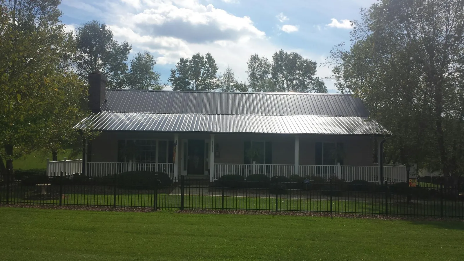 Gray metal roof on a brick ranch with a full width front porch — Gutter Guard Installation work by our crew in Norris